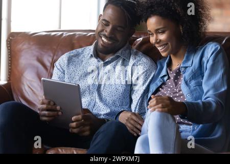 Laughing African couple watch video on digital tablet Stock Photo