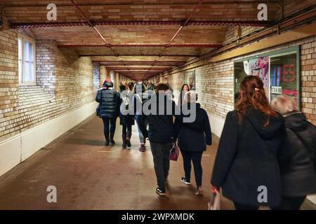 London, United Kingdom - February 01, 2019: Commuters in winter clothes walking through tunnel to Kensington tube station, view from behind Stock Photo