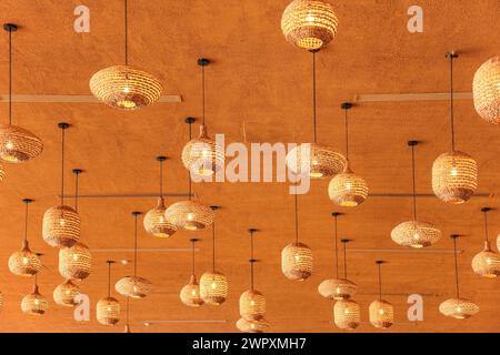 Stylish irregular straw like lamp shades on orange ceiling Stock Photo