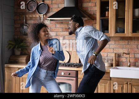 Lively millennial African couple dancing in kitchen at home Stock Photo