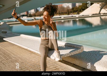Portrait of sporty smiling young woman after running making selfie outdoors Stock Photo