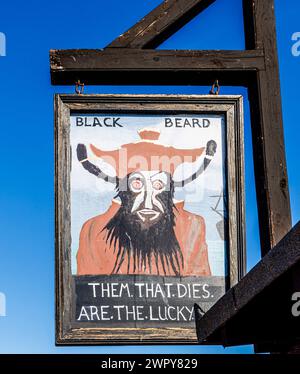 Amusing wooden painted sign with Blackbeard and 'them that dies are the lucky ones' in the Stade in the Old Town of Hastings, East Sussex, England Stock Photo