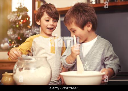 Boys, baking and happy in kitchen with flour, home and learning with ingredients for christmas cake. Children, mixing or bowl for cookies on counter Stock Photo