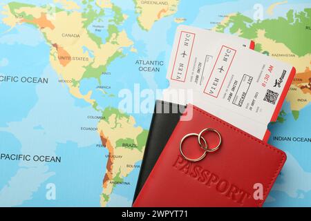 Honeymoon concept. Plane tickets, passports and golden rings on world map, top view Stock Photo