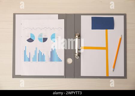 Business process planning and optimization. Document with different types of graphs and pencil in folder on wooden table, top view Stock Photo