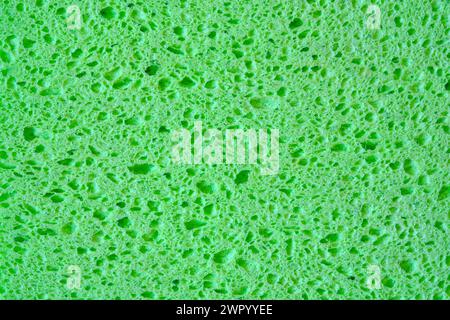 Green sponge with pores texture background for graphics. Close-up macro photo of household sponge tissue. Stock Photo