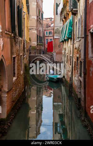 A small waterway on a quiet Sunday morning with a small boat and laundry on the house facades. Stock Photo