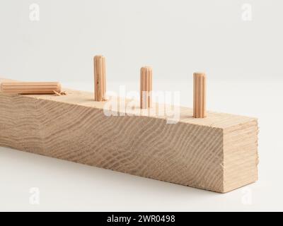 Wooden fluted dowel pins fixed in a wooden board isolated on a white background Stock Photo