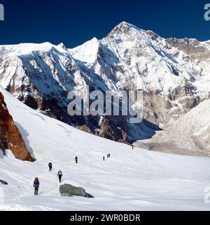 Mount Cho Oyu and group of hikers on glacier, way to Cho Oyu base camp , Everest area, Sagarmatha national park, Khumbu valley, Nepal Himalayas mounta Stock Photo