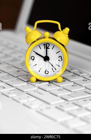 Alarm clock on a laptop computer keyboard. Daylight savings time background. Stock Photo