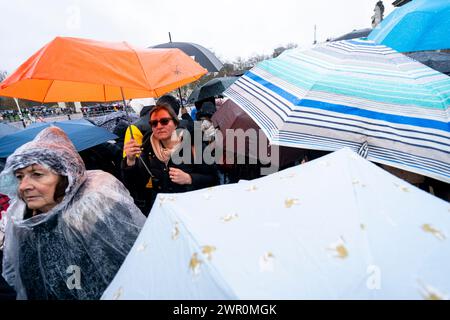 Members of the public shelter from the rain at Buckingham Palace, London. Picture date: Sunday March 10, 2024. Stock Photo
