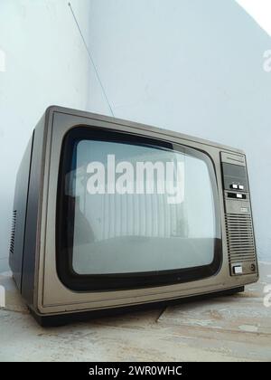 Vintage TV on concrete floor against white wall Stock Photo