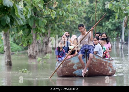 Sragen, Indonesia. 10th Mar, 2024. People ride a wooden boat on floodwater after heavy rain and overflow of Bengawan Solo River at Pandak village in Sragen district, Central Java, Indonesia, on March 10, 2024. Credit: Bram Selo/Xinhua/Alamy Live News Stock Photo
