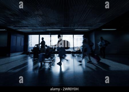 People at an airport terminal, walking with luggage and sitting, waiting for their departure time, motion blur shot. Traveling and transport concepts. Stock Photo