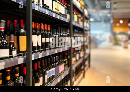 Liquor store concept. Wine bottles on shelves in the wine shop. Stock Photo