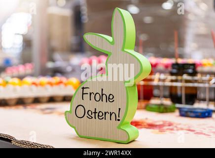 Thannhausen, Bavaria, Germany - March 10, 2024: Happy Easter, greeting on a wooden Easter bunny in an egg dyeing factory. PHOTOMONTAGE *** Frohe Ostern, Gruß auf einem Holz Osterhase in einer Eierfärberei Fabrik. FOTOMONTAGE Stock Photo