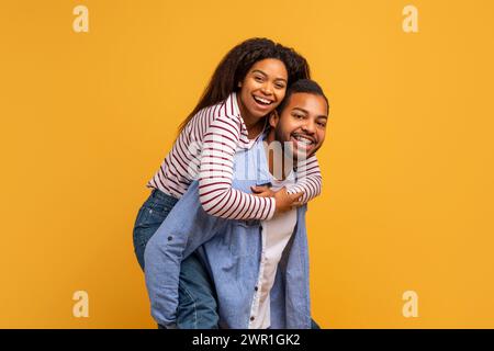 Happy laughing young black couple having fun against yellow studio background Stock Photo