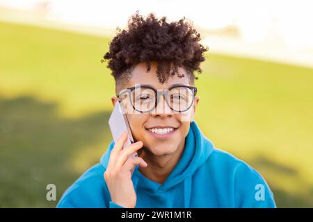 Portrait of smiling black student guy talking on cellphone outdoors Stock Photo