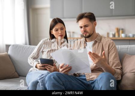 Confused spouses reviewing documents with tablet Stock Photo