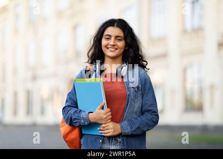 Positive middle eastern lady student posing at university campus Stock Photo