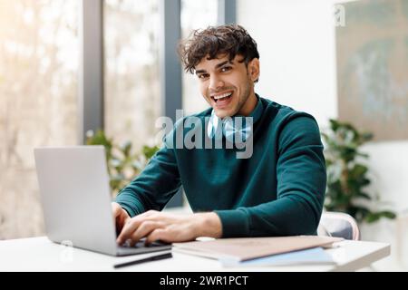 Happy man with headphones using laptop and smiling at camera Stock Photo