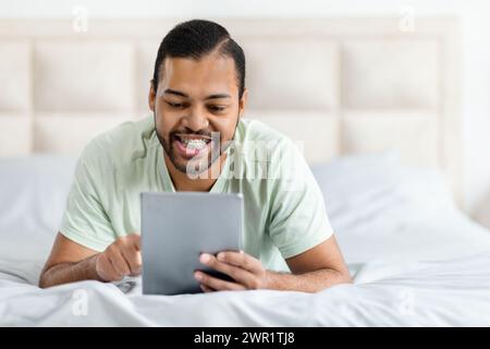 Relaxed happy african american man using digital tablet and smiling Stock Photo