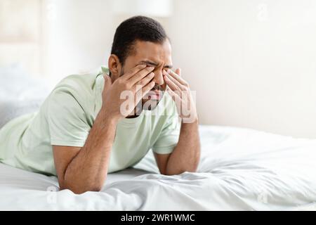 Closeup of upset black man laying on bed, crying Stock Photo