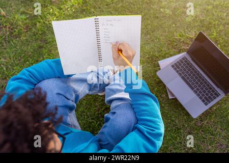 Rear view of student guy writing academic schedule sitting outdoors Stock Photo