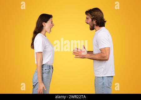 Intense young couple in white t-shirts engaging in a verbal disagreement or animated conversation Stock Photo