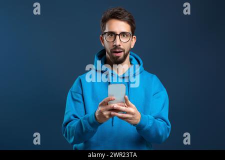 Mobile Offer. Surprised man holding smartphone and looking at camera with excitement Stock Photo