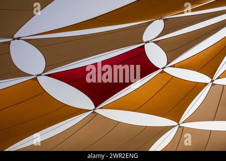 Colorfully Sun Tent on Blue Sky. Yellow, Orange and Red Shade Sails Pattern. Stock Photo
