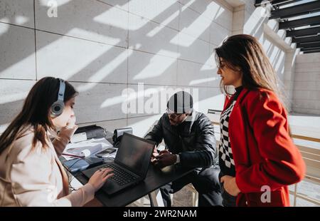 Diverse team collaborating on project outdoors with laptop and documents. Stock Photo