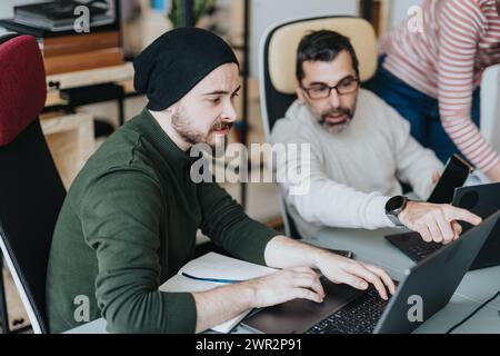 Successful collaboration of male businesspeople in a modern office using laptop and discussing project solutions. Stock Photo