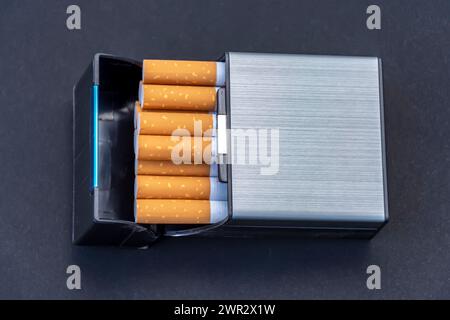In a plastic cigarette case with cigarettes on a black background, top view. Stock Photo