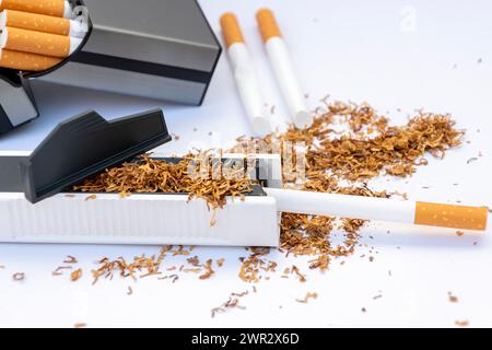 Manual machine for stuffing cigarette casings with tobacco, scattered empty cigarettes and a pile of tobacco on a white background, cigarette case wit Stock Photo