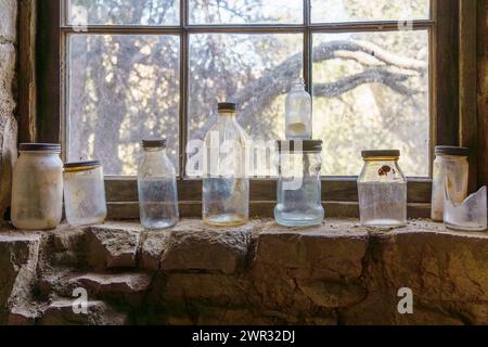 Old antique glass bottles sitting in a row on a window sill of Eagle Cliff Mine cabin at Joshua Tree National Park, California Stock Photo