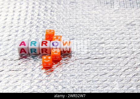 Arrow composed with letter cubes and expressions of happiness on silver background Stock Photo