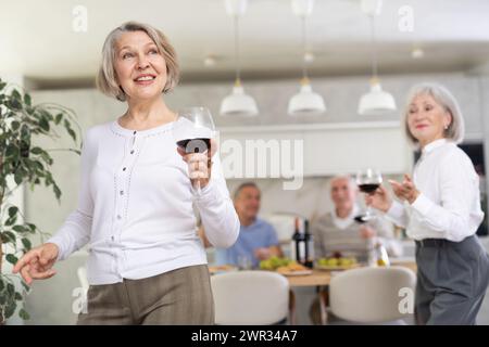 Senior men and women have fun dancing during house party. Stock Photo