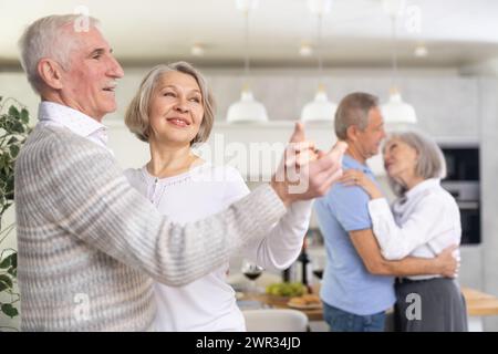 Two married couples enjoying slow dancing at house party for friends Stock Photo