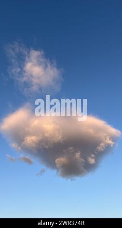 Lonely gray cumulus cloud at sunset with blue sky Stock Photo