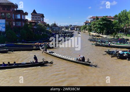 People on boats on a river with city silhouette in the background, Pindaya, Inle Lake, Myanmar Stock Photo