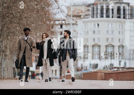 Three young business professionals discuss strategies while walking through a cityscape, showcasing dynamic remote working. Stock Photo