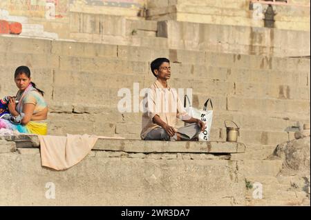 Single person praying on the steps of the ghats in the morning light, Varanasi, Uttar Pradesh, India Stock Photo
