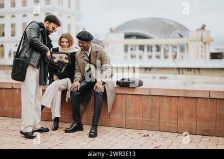 Three young business entrepreneurs interact while focusing on a digital tablet during an outdoor meeting in a bustling city backdrop. Stock Photo