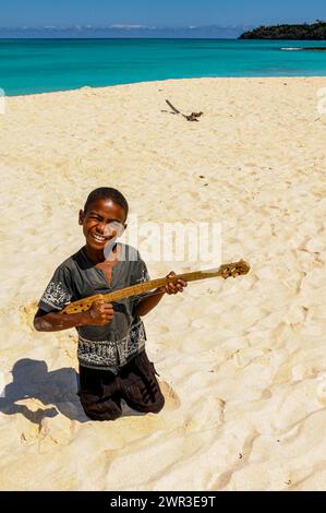 Boy playing on a hand made guitar, Nosy Iranja near Nosy Be, Madagascar Stock Photo