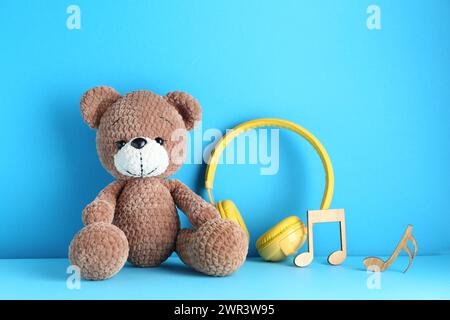 Baby Songs. Toy Bear And Yellow Headphones On Light Blue Background 