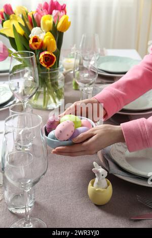 Woman setting table for festive Easter dinner at home, closeup Stock Photo