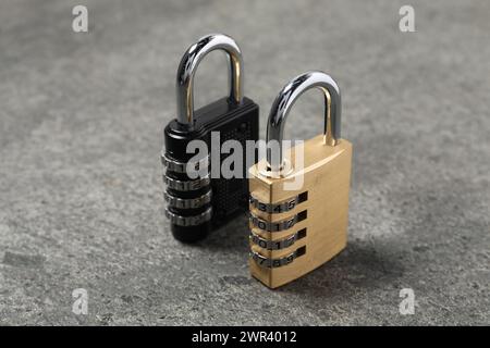 Locked steel combination padlocks on grey stone table, closeup Stock Photo