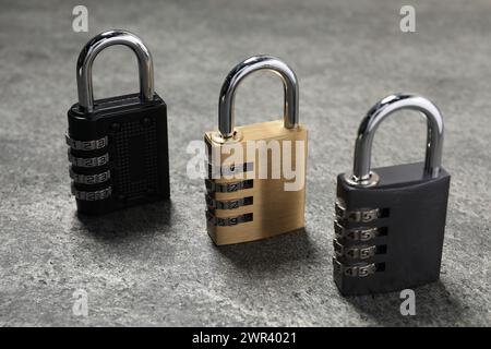 Locked steel combination padlocks on grey stone table, closeup Stock Photo