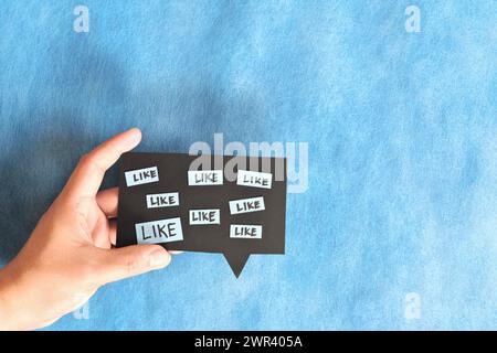 Hand holding a speech bubble like reactions. Social media high engagement concept. Stock Photo